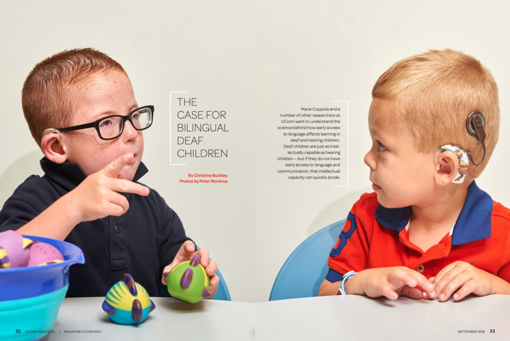 Image showing two Deaf children, one with a hearing aid and one with a cochlear implant, using sign language while playing together. 